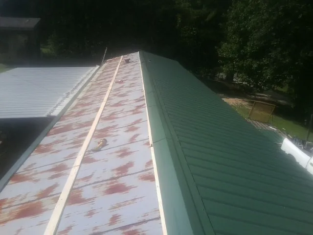 Old rusted panels beside newly installed green metal roofing — Wind Damage Roof Repair by Roofing Brothers in Osawatomie