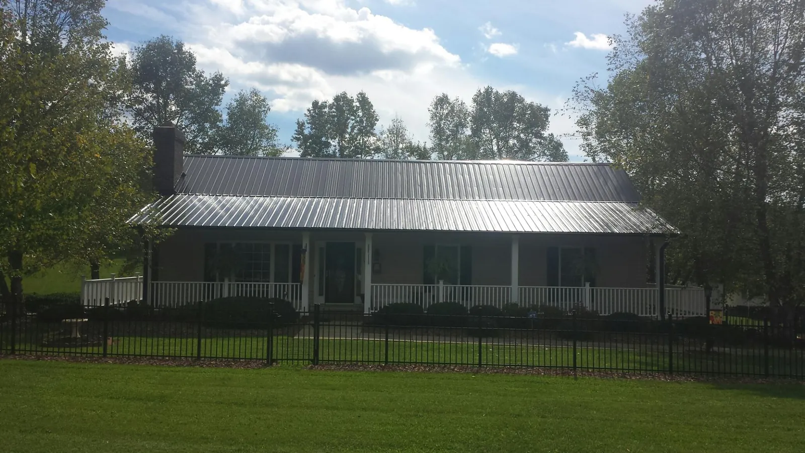 Gray metal roof on a brick ranch with a full width front porch — Gutter Guard Installation work by our crew in Osawatomie