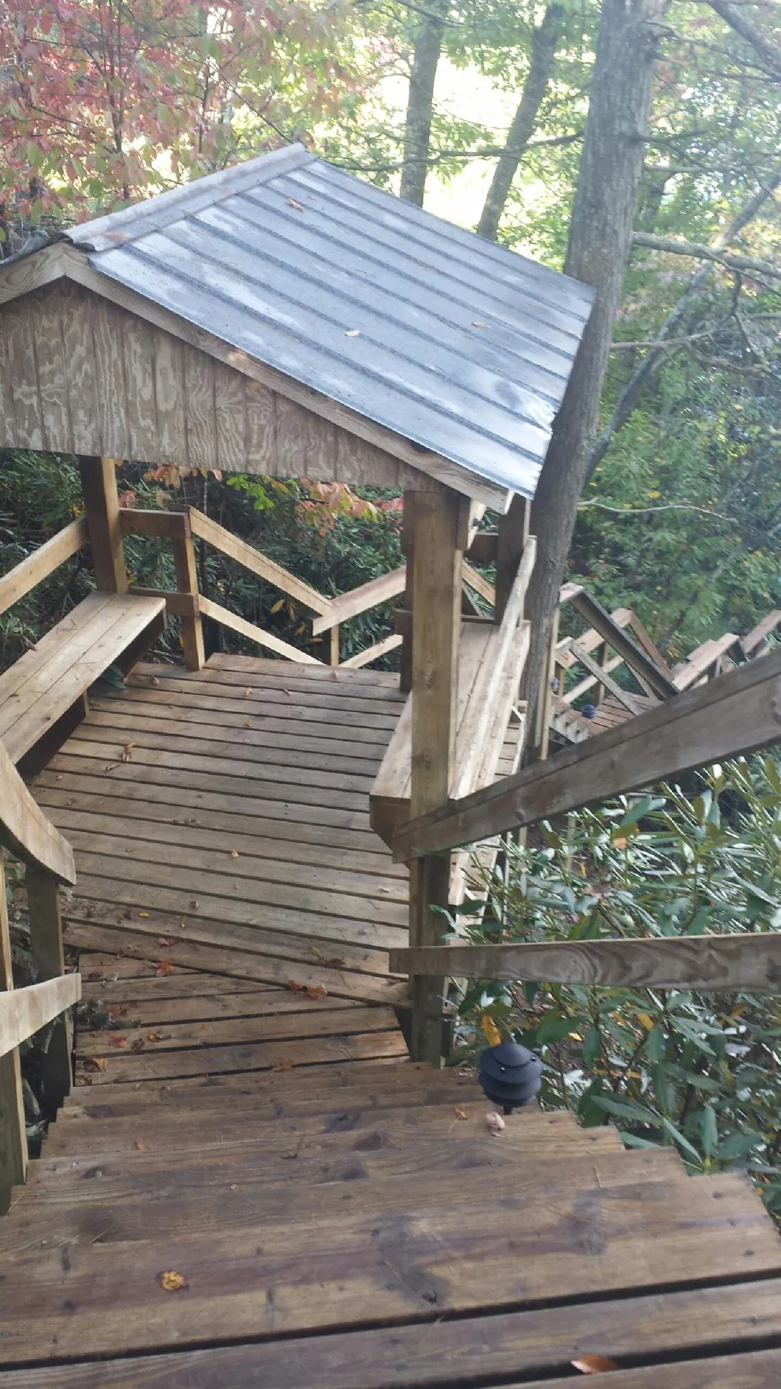 Metal roofed shelter over wooden steps on a wooded walkway — Skylight Repair & Installation work by our crew in Osawatomie